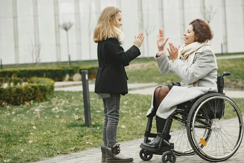 Woman in wheelchair playing with child in a park, representing NDIS community participation