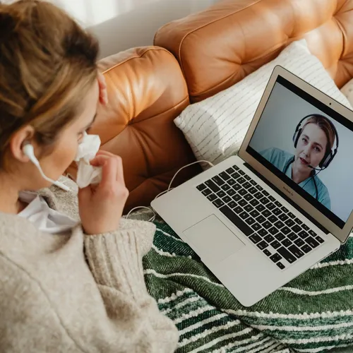 Client attending a telehealth therapy session via laptop from home